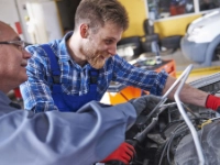 Zwei Kfz-Mechatroniker inspizieren den Motor eines Autos